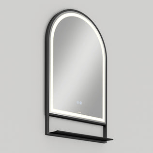 The Artika Arturo 20 in. x 32 in. LED mirror features an arched design, 3 CCT lighting with a defogger, black frame, touch controls, and a small black shelf—shown mounted on a light gray wall.