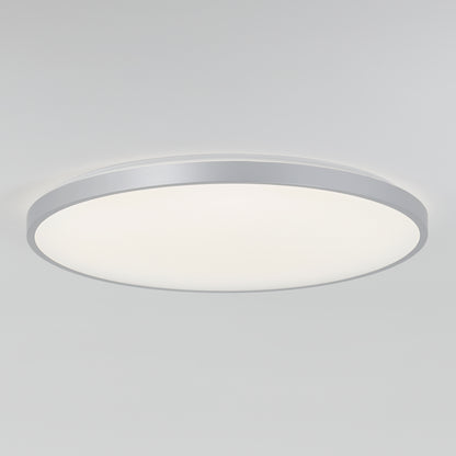 The Artika Jupiter 23 in. LED flush mount light features a modern round design with a white diffused cover and silver rim, mounted on a plain white ceiling. Includes remote control.