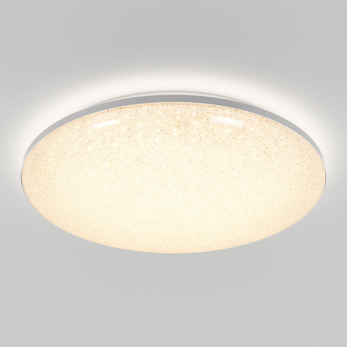 A round, flush-mounted ceiling light fixture with a glowing, textured surface emits soft, warm light against a plain white ceiling.