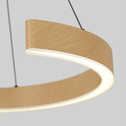 A close-up of a modern, circular pendant light with a wood-textured exterior and integrated LED lighting, suspended by two thin cables against a plain gray background.