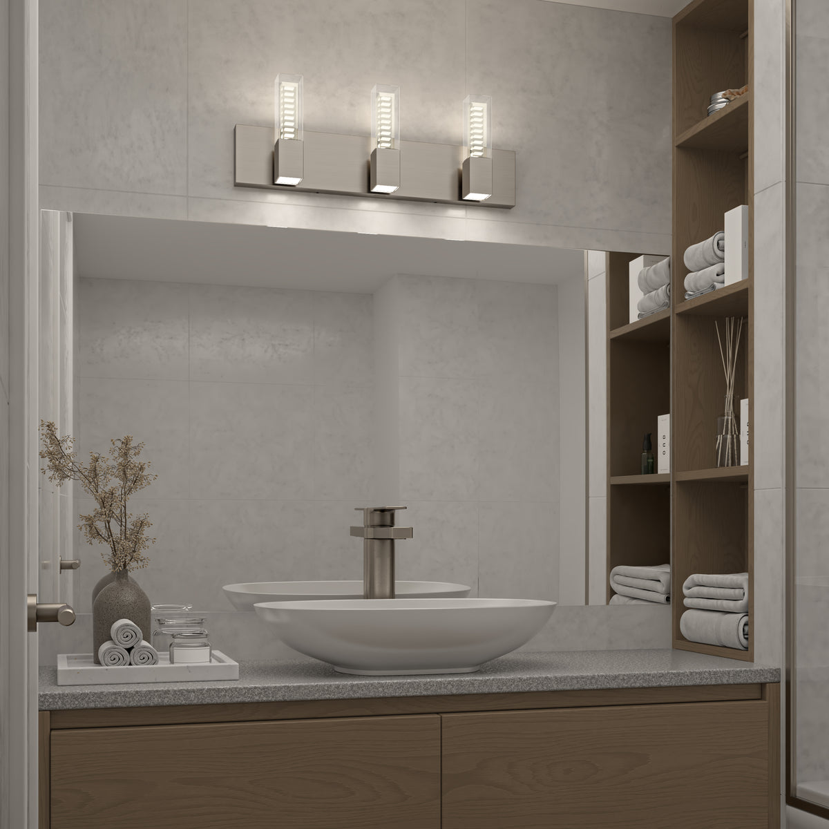 Modern bathroom with a large mirror, vessel sink, sleek faucet, and wooden shelves holding folded towels and decor. Three contemporary lights are mounted above the mirror, and a vase with dried branches sits by the sink.