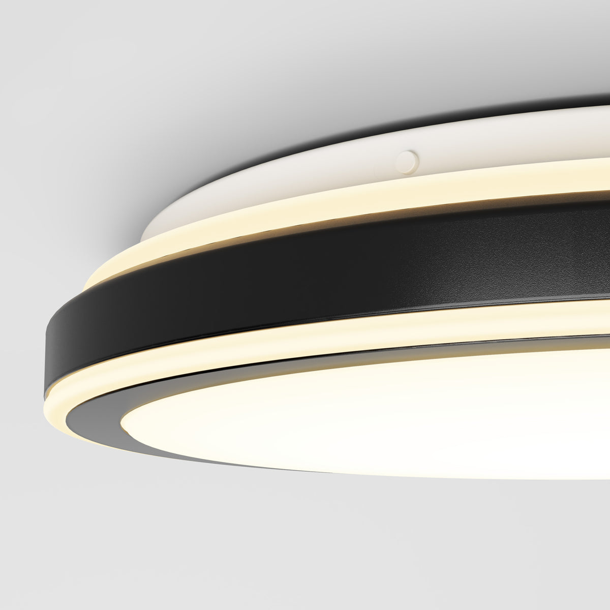 Close-up of a modern, circular ceiling light fixture with a black and white design and built-in LED lighting, mounted on a white ceiling.