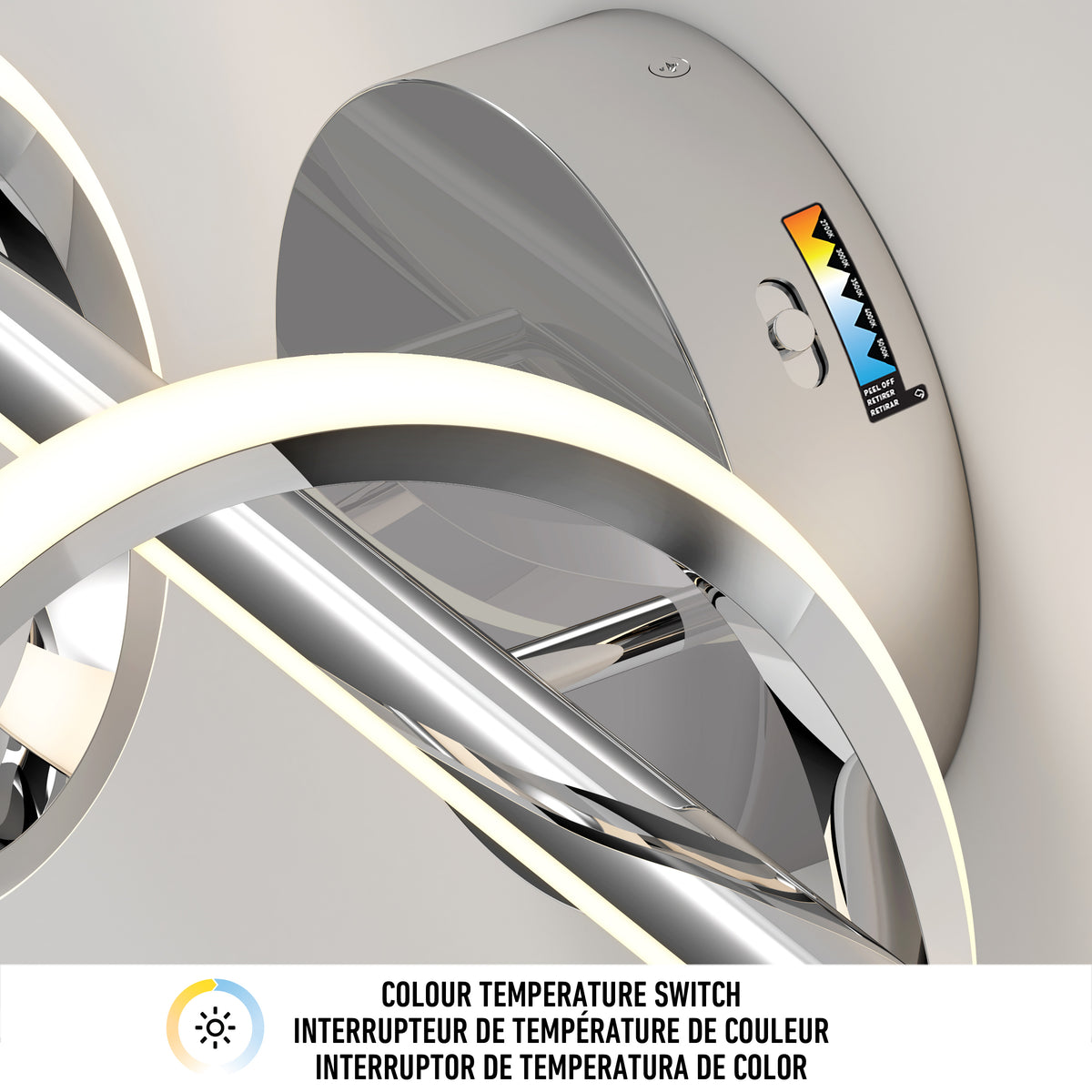 Close-up of a modern, circular LED light fixture with a chrome finish, featuring a color temperature switch and a multicolored temperature indicator label. Below is a label in English, French, and Spanish about the switch.