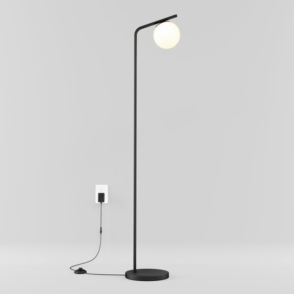 The Artika Clayton dimmable LED modern mid-century floor lamp in black stands on a minimalistic white background, featuring a round white bulb, visible cord, and floor switch.