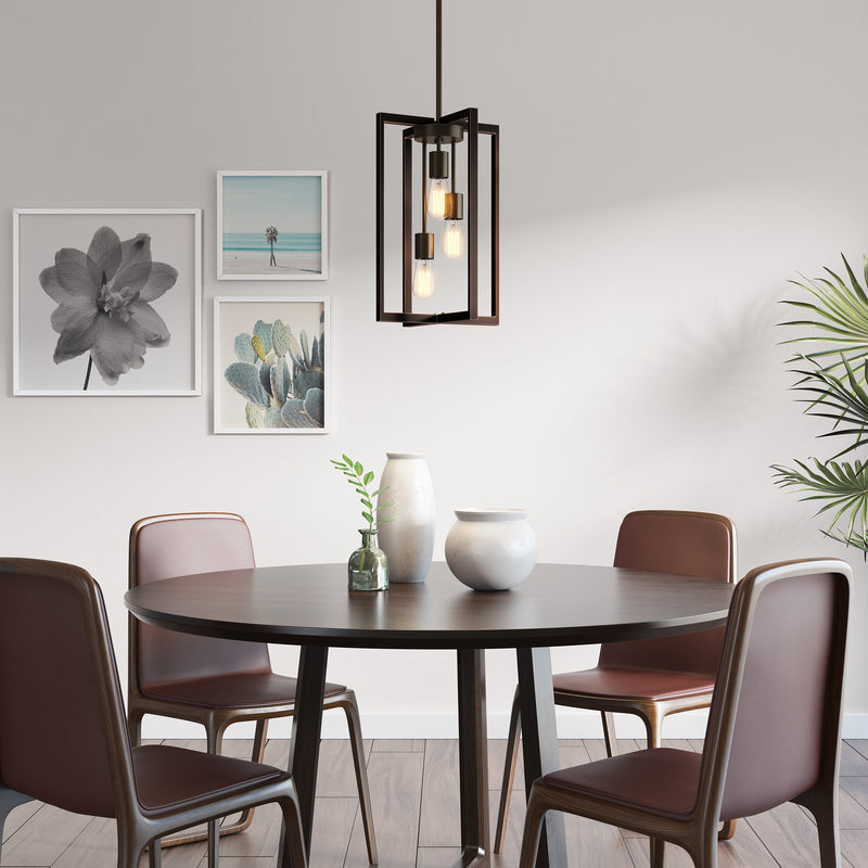 Modern dining area with round dark table, four brown chairs, vases, wall art, and Artika’s Yale 3-light Chandelier above a potted plant.