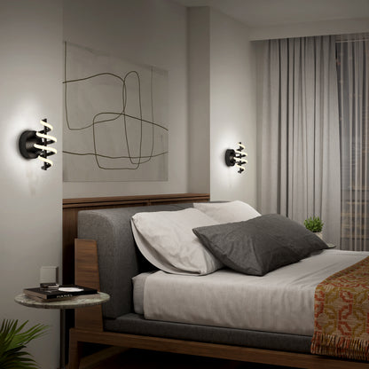 A modern bedroom features a wooden bed with white and gray bedding, abstract wall art, a round marble nightstand with a book and cup, two Artika Chorus LED Wall Lights, and sheer curtains covering the window.