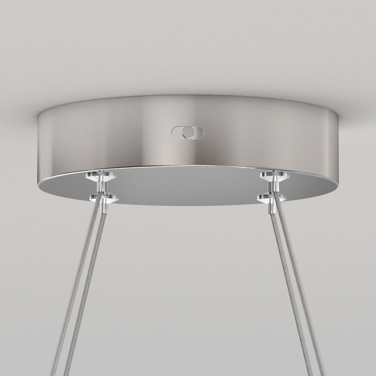 A close-up of a metallic ceiling canopy with four cables attached, likely for suspending a modern light fixture, against a plain white ceiling.