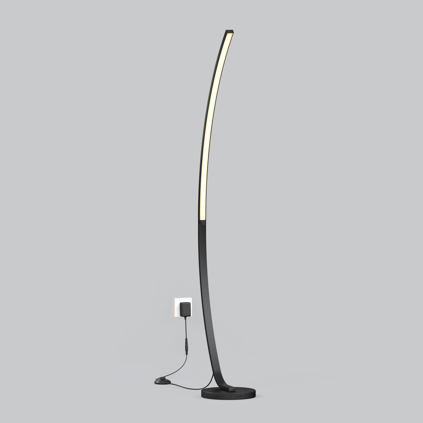 The Artika Arc LED Floor Lamp features a slim, curved black design with integrated LED lighting, standing plugged into a wall outlet against a plain light gray background.