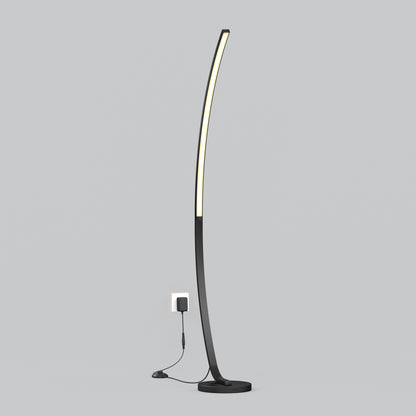 The Artika Arc LED Floor Lamp features a slim, curved black design with integrated LED lighting, standing plugged into a wall outlet against a plain light gray background.