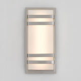A modern rectangular wall sconce with a frosted glass panel, framed by a metallic border and three horizontal metal bars across the front, emitting soft, diffused light against a plain light gray wall.