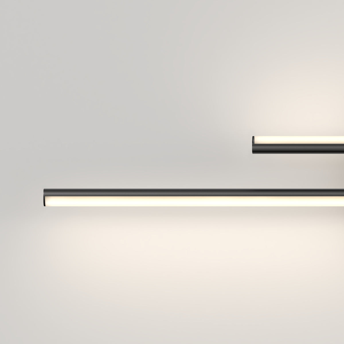Two minimalist, horizontal LED light bars mounted on a plain white wall, emitting soft, white light and creating a clean, modern look. One light is longer and placed lower than the shorter, upper light.