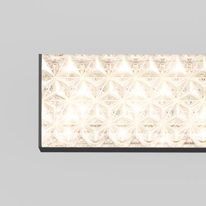 A close-up of the Adeline modern LED bathroom vanity light 3 CCT by Artika, featuring a rectangular shape with diamond-patterned glass and emitting a warm, bright glow against a plain light gray background.