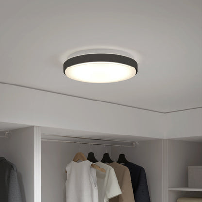 An Artika Sunraker 10 in. LED modern flush mount light with a black rim brightens a closet, illuminating hanging clothes and partially visible shelves below.
