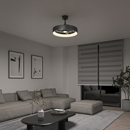A modern living room features a sectional sofa, minimalist decor, abstract wall art, a round black coffee table, large gray blinds, and a potted plant. The ceiling is illuminated by the Artika Austin 23 in. LED modern ceiling fan with remote.