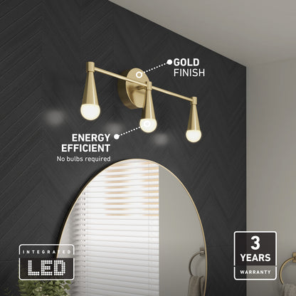 The Artika Wayden LED mid-century bathroom vanity light 3 CCT, featuring a gold finish and energy-efficient integrated LED bulbs, is mounted above a round mirror on a dark chevron wall; a 3-year warranty label is visible.