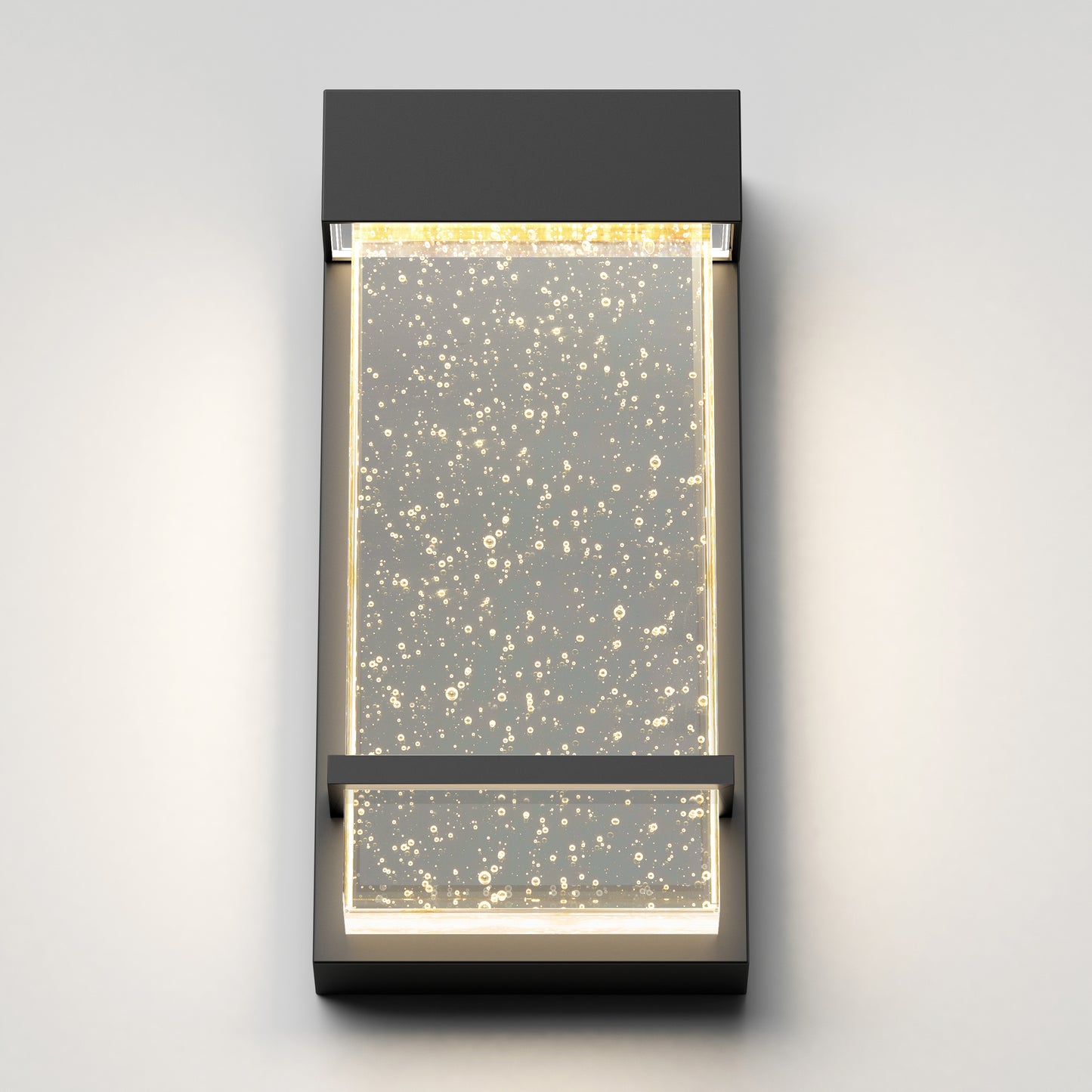 The Skyler indoor-outdoor LED wall light by Artika features a modern rectangular design with a clear panel of embedded air bubbles, illuminated warmly from the top and sides.
