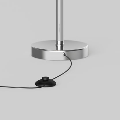 A close-up of the Artika Pivot modern LED floor lamp 3 CCT, featuring a chrome base with a black power cord and round black foot switch on a light gray background.