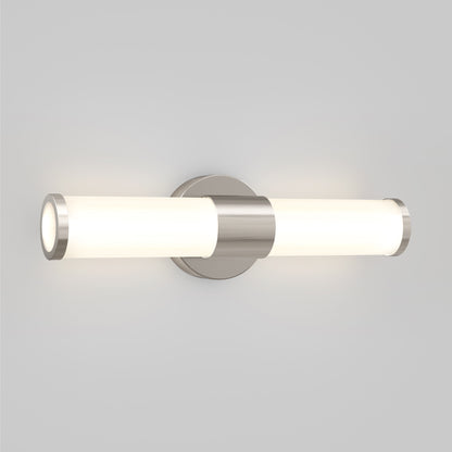 The Artika Adina modern bathroom vanity light 3 CCT features a sleek wall-mounted design with two horizontal frosted glass shades and a brushed metal base, casting soft white light against a plain light gray wall.