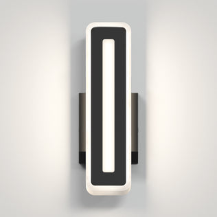 The Artika Evasion modern indoor-outdoor LED wall light 3 CCT features a rectangular black frame and vertical white illuminated center, mounted on a light gray wall to cast soft, dual-sided light.