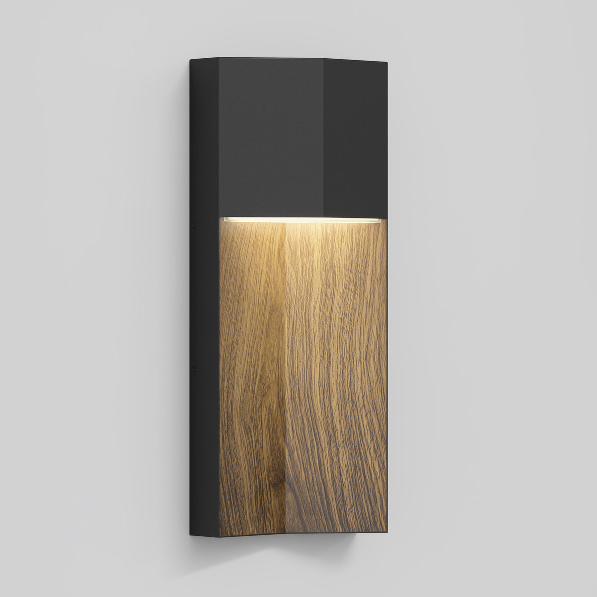 A modern wall sconce with a matte black top and a wood-grain finish on the lower half, emitting a soft light downward against a plain light gray background.