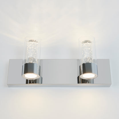 The Artika Ratio 2-light LED bathroom vanity light features a rectangular chrome base and two bubble glass shades, emitting bright white light, and is shown mounted on a white wall.
