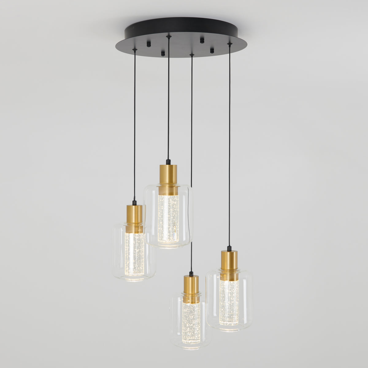 A modern ceiling light fixture with four hanging pendant lights, each featuring a gold-toned base, clear glass shade, and black cords attached to a round black ceiling mount.