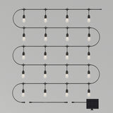 A string of hanging lightbulbs arranged in a zigzag pattern, connected by a black wire, with a small attached solar panel at the bottom right, set against a plain gray background.