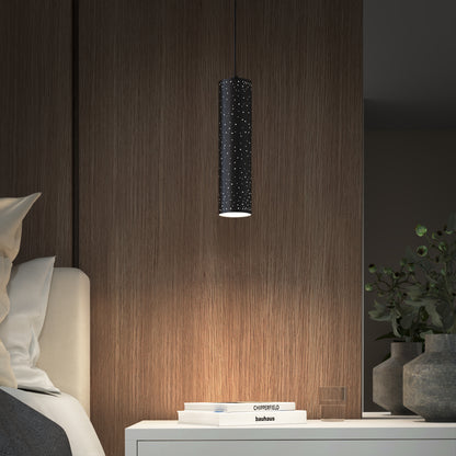 A modern bedroom nightstand with stacked books, a small glass, a green plant in a vase, and the Artika Cosmic modern LED pendant light 3 CCT casting patterned light onto a wooden wall.