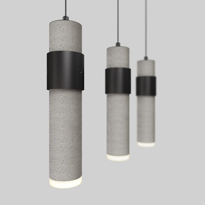 The Barden 3-light LED pendant light by Artika features three modern cylindrical lights with concrete-style bodies, black metal center bands, and cord suspension, hanging in a row against a plain gray background.