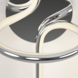 Close-up of a modern, metallic light fixture with curved, tubular arms and a circular base, featuring a sleek chrome finish and integrated LED lighting.