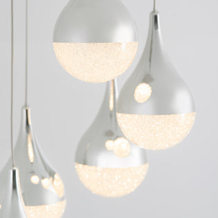 Close-up of Artikas Glitzer 5-light LED pendant, showcasing teardrop and round chrome-finished lights with textured, sparkling illuminated lower halves against a light gray background.