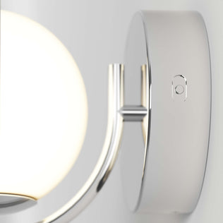Close-up of the Artika Bloom LED Sconce 3 CCT, a modern wall-mounted fixture with a round frosted glass shade and shiny metallic base, shown on a light-colored wall.