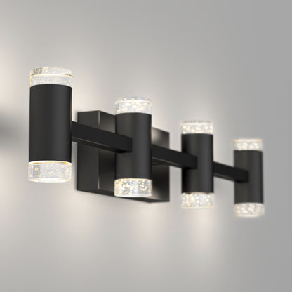 The Artika Mist modern LED bathroom vanity light 5 CCT features four black cylindrical lamps with clear textured ends, casting a soft white glow against a light gray wall.