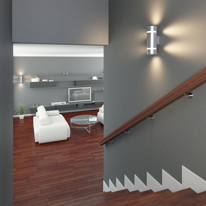 A modern living room with white furniture, wood floors, gray walls, and built-in shelving, viewed from a staircase with a wooden handrail and Artikas Q1 indoor-outdoor wall light providing contemporary illumination.
