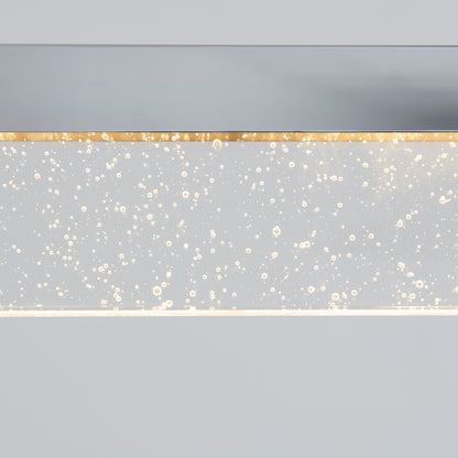 The Artika Essence Bar LED pendant light features a rectangular, transparent surface with embedded bubbles that glow softly, creating a sparkling, airy effect against a light gray background.