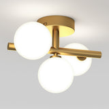 Modern ceiling light fixture with three frosted glass globes attached to a gold metal base and arms, mounted on a white ceiling. The globes emit a soft, diffused glow.