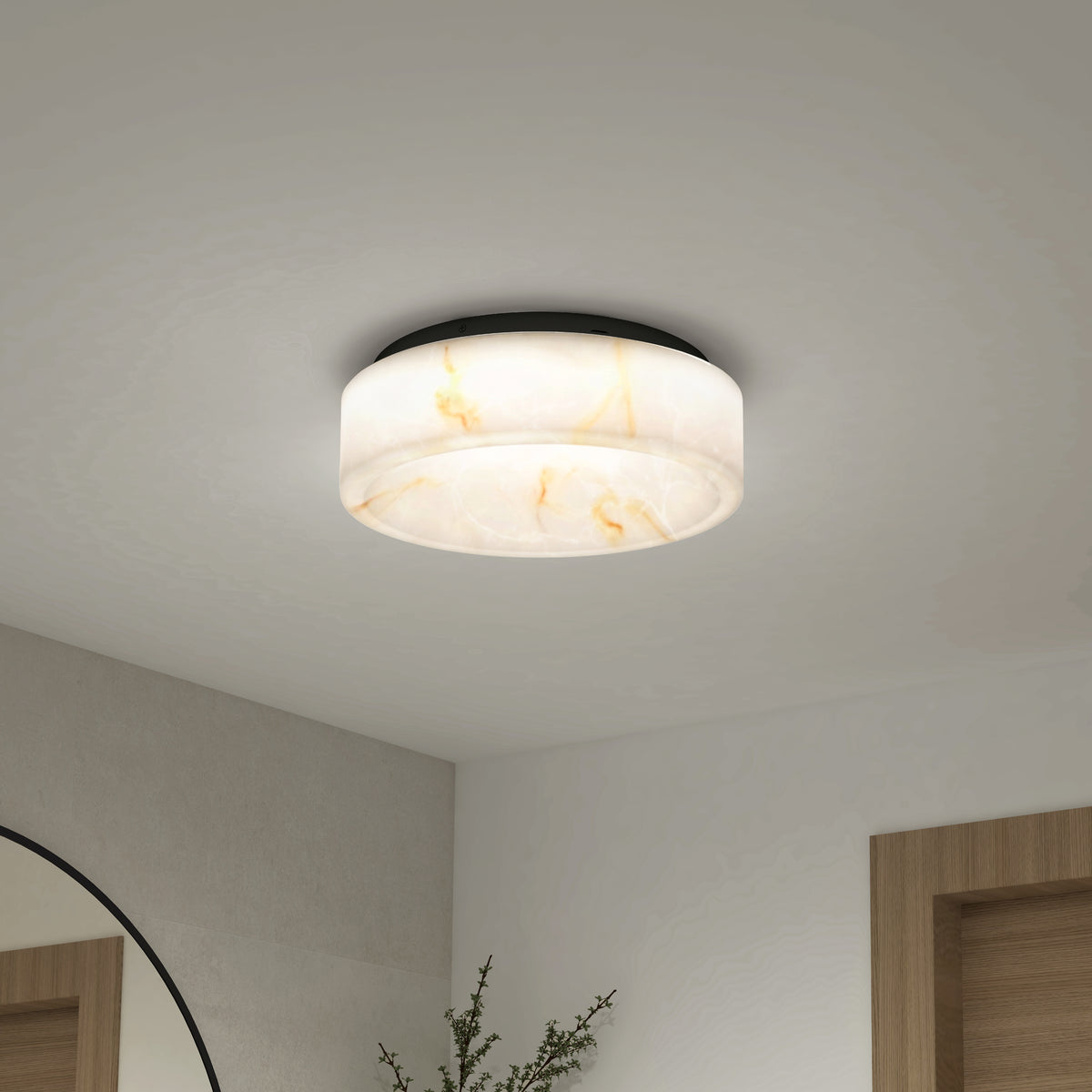 A modern, round ceiling light with a white and beige marbled pattern is mounted on a white ceiling. Part of a mirror, plant, and wooden door frames are visible in the minimalist room below.