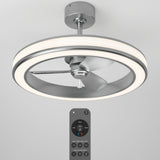 Ceiling fan with three silver blades and a circular LED light ring, mounted on a silver base. A remote control with multiple buttons is shown below the fan. The background is plain light gray.