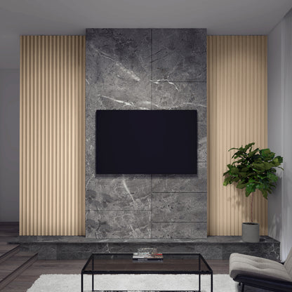 A modern living room features an Artika Panolok 30.67 ft wall panel kit (pack of 8) as a gray marble accent wall with a wall-mounted TV, vertical wooden panels, a green potted plant on the right, and a glass coffee table in front.