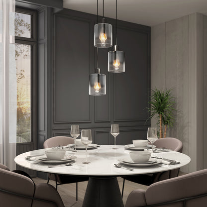 A modern dining room with a round marble table for four, pink upholstered chairs, an Artika Haze modern 3-light glass pendant light overhead, a potted plant in the corner, and large windows filling the space with natural light.