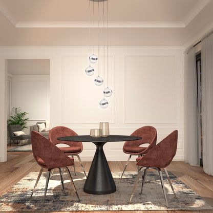 A modern dining room features a round black table, four reddish-brown velvet chairs, wood floors, a patterned rug, and the Artika Wavey 5-light LED pendant illuminating the open space with views into the living area and a green plant.