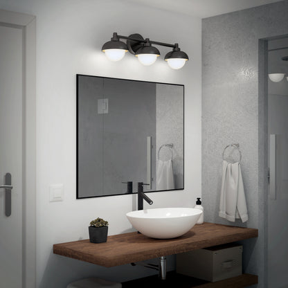 Modern bathroom with wooden countertop, vessel sink, black faucet, mirror, white towel on a ring, soap dispenser, small potted plant, light gray walls, and a partially visible door and shower. Features the Artika Boden LED mid-century vanity light 5 CCT.