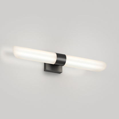The Artika Wilton LED modern bathroom vanity light 5 CCT features a horizontal frosted tube and a black rectangular base, mounted on a light gray wall.