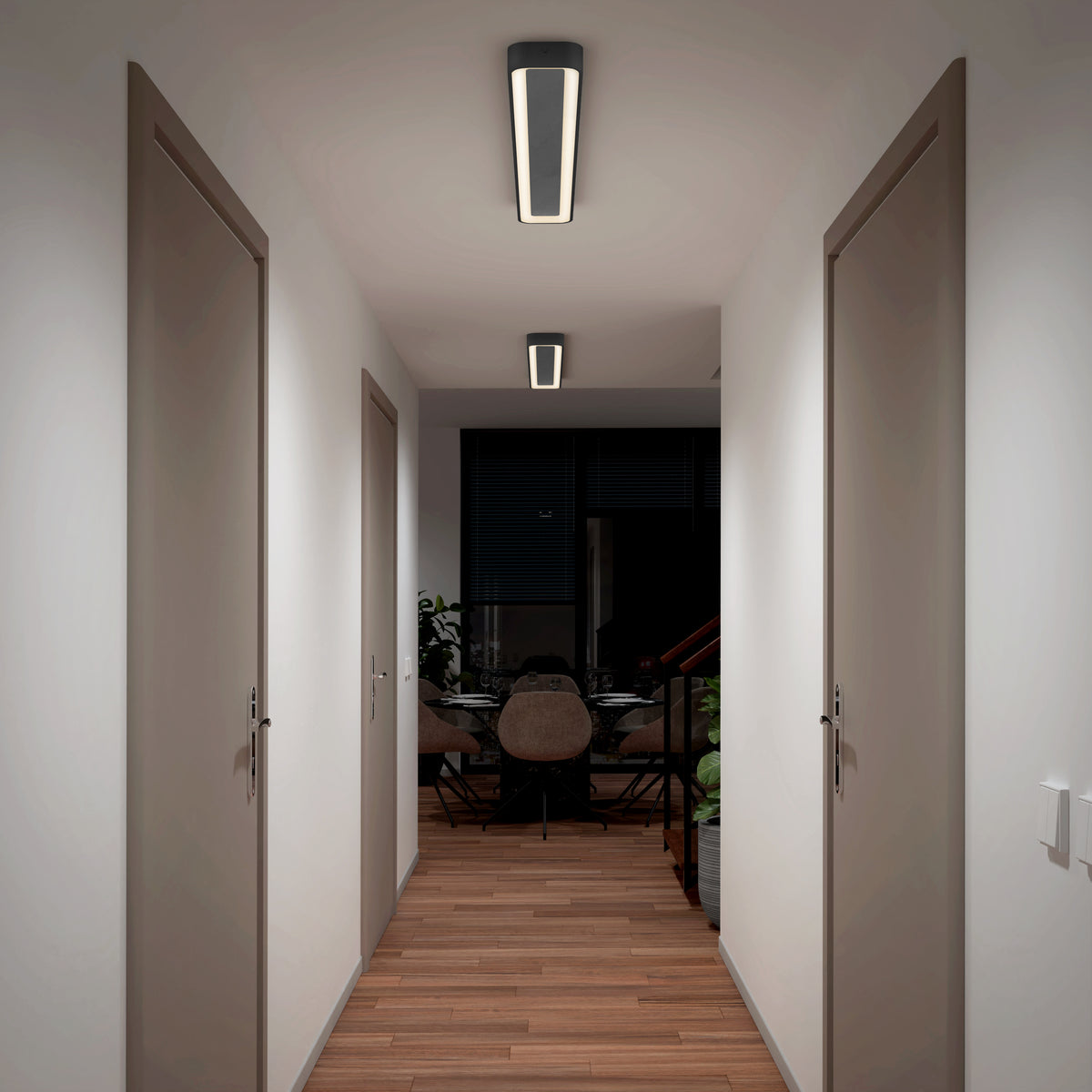 A modern hallway with wooden floors, white walls, two closed doors on each side, and ceiling lights. At the end of the hallway is a dining area with chairs, a table, and large windows.