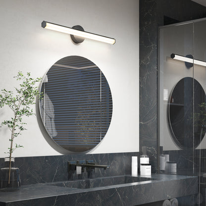 Modern bathroom featuring the Artika Ewen modern LED bathroom vanity light (5 CCT) above a round mirror, black marble countertop, small potted plant, toiletries, and window with blinds reflected in the mirror.