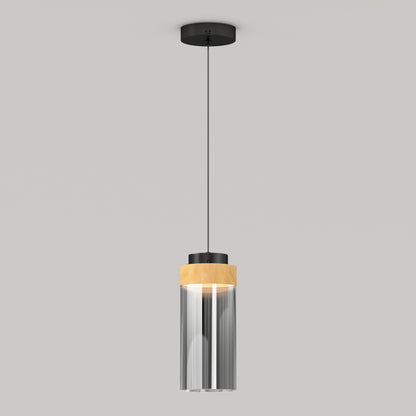 The Artika Hanson 1-light LED pendant 5 CCT features a black ceiling mount, slim black cord, and a cylindrical glass shade with a wooden accent at the top, shown against a plain light gray background.