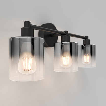 The Artika Haze modern 3-light bathroom vanity light features exposed bulbs in cylindrical clear glass shades and a dark metal frame, casting a warm glow against neutral walls.