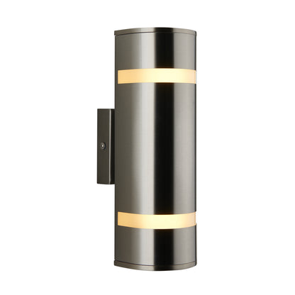 The Artika Q1 indoor-outdoor wall light features a modern cylindrical design in brushed metal with two horizontal frosted bands, emitting soft light from a rectangular wall plate.