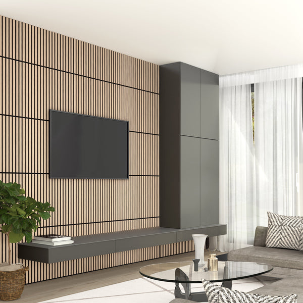 A modern living room features a TV on the Artika-CAN-dev Sonolok 15.5 ft sound-absorbing wall panel kit, floating cabinets, a round glass coffee table, gray sofa, potted plant, and sheer white curtains letting sunlight in.