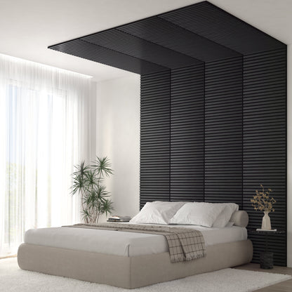 A modern bedroom features a beige bed with white bedding and a Sonolok 15.5 ft sound-absorbing wall panel kit by Artika-CAN-dev as a black slatted accent wall extending onto the ceiling, plus large windows, sheer curtains, a potted plant, and vase on a side table.